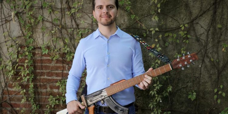 El Titular de Cultura en Culiacán causa polémica al posar con fusil AK-47 convertido en guitarra
